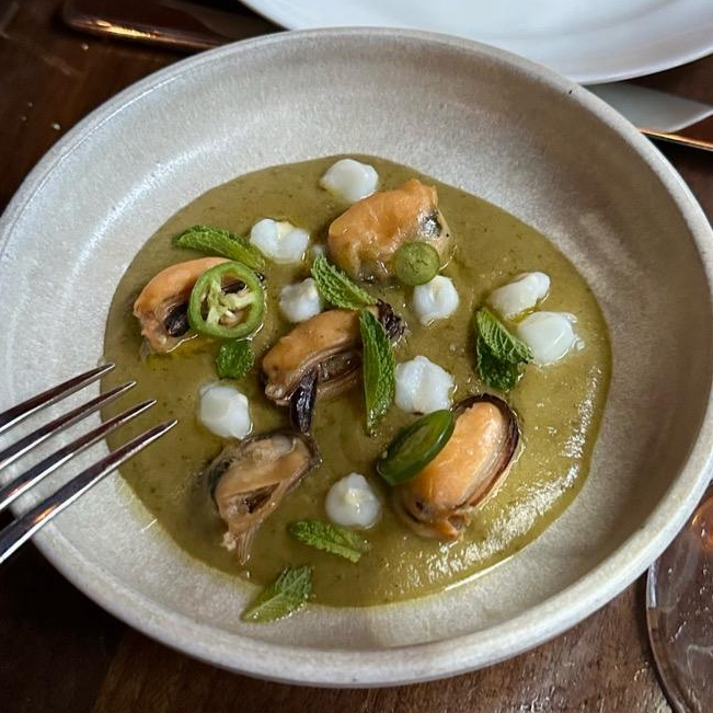Photo of clams in coconut tomatillo sauce from Sueños X Soho Friends